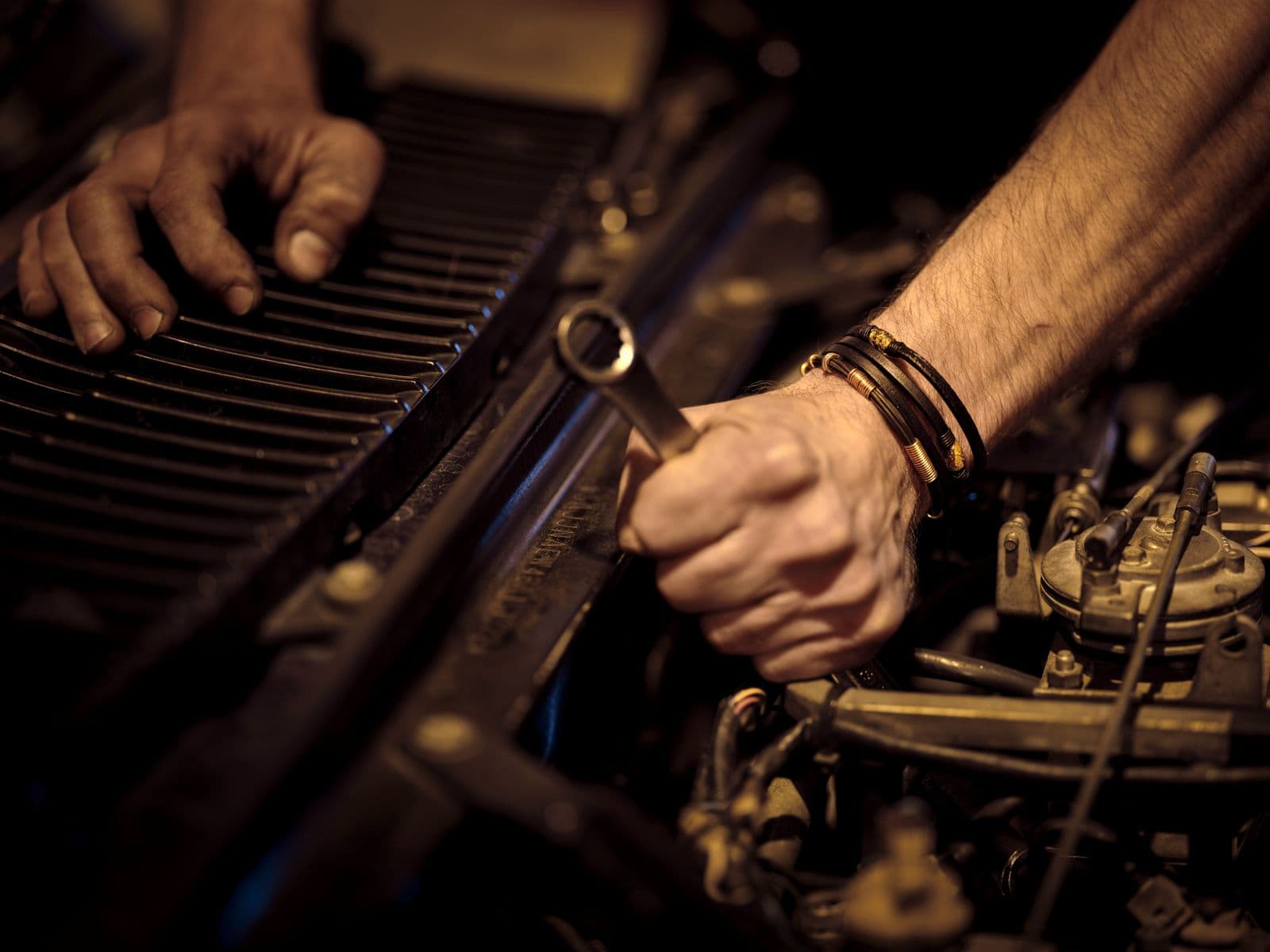 Hands working a wrench on a vintage engine