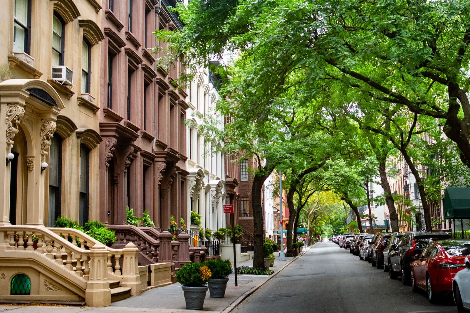 Cars parked along a brownstone street in summer