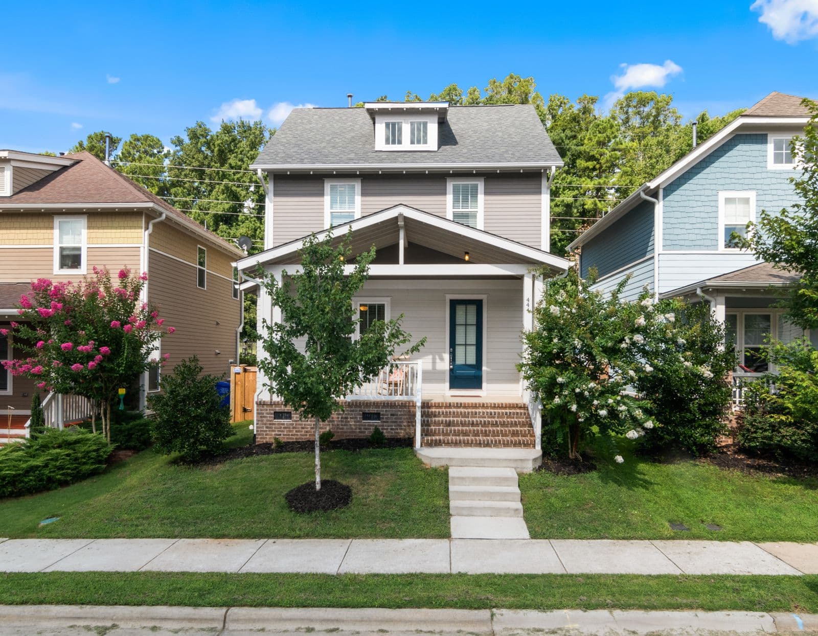 Gray house with a covered front porch on a tree-lined street