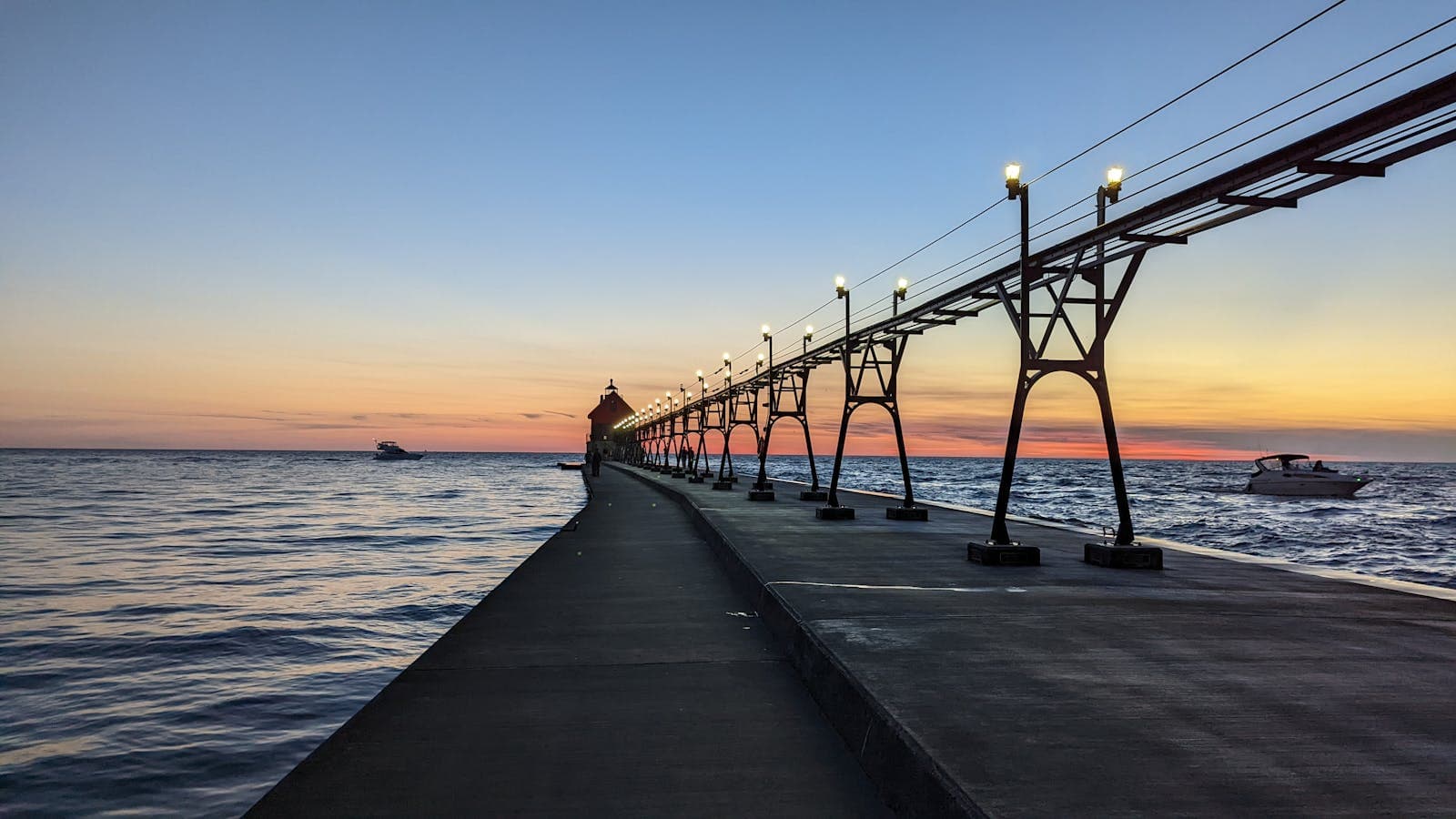 The lighted catwalk and lighthouse on South Haven's pier stretching into Lake Michigan at dusk.