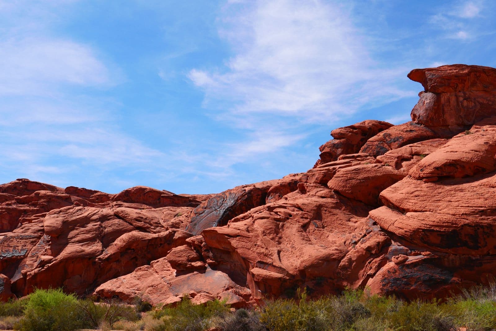 Vivid red sandstone formations of Valley of Fire State Park rise under a bright blue desert sky.