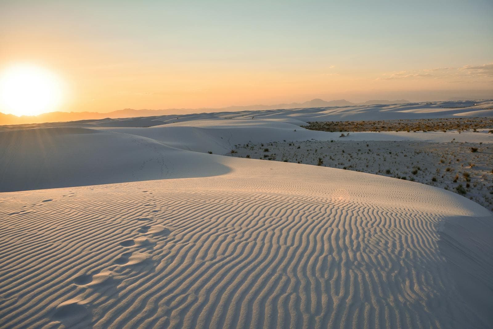 Golden sunset light washes over rippled white gypsum dunes at White Sands, New Mexico.