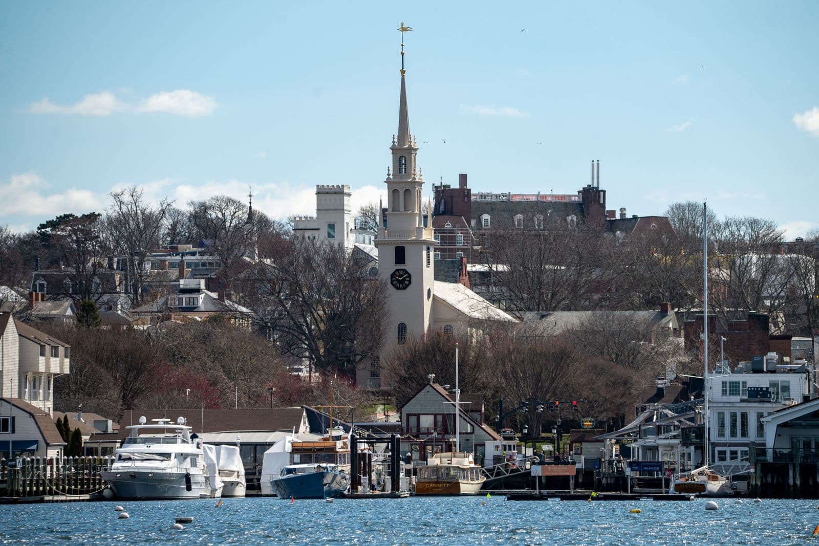 Sailboats fill Newport Harbor along the Rhode Island waterfront with a historic church steeple rising above the town.