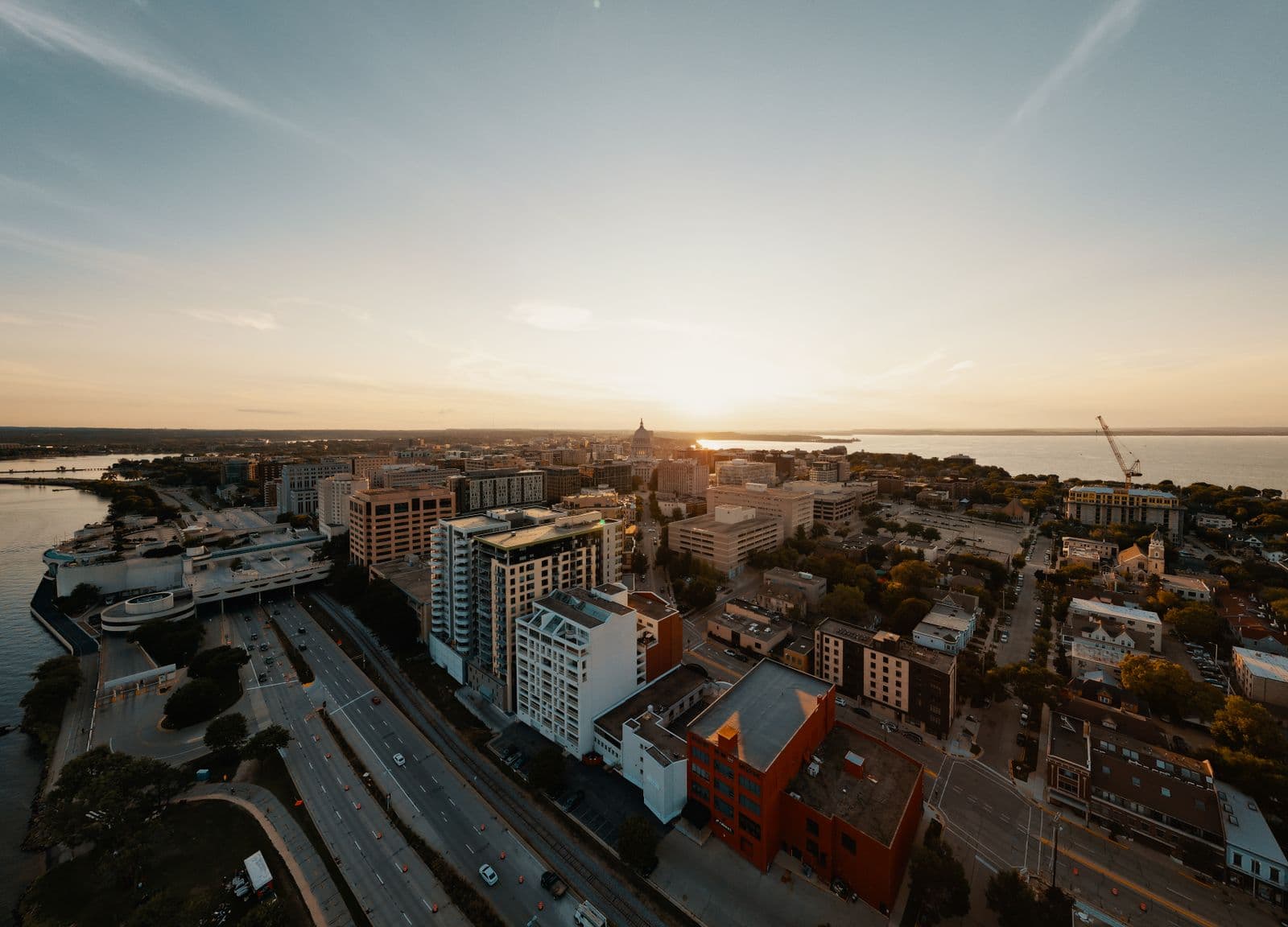 Aerial view of Madison's isthmus at sunset with the Wisconsin State Capitol dome silhouetted between two lakes.